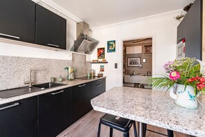 A modern kitchen with black cabinets, a granite countertop, and a stainless steel range hood. - Le Lyautey - Charmant appt avec terrasse (Ajaccio)