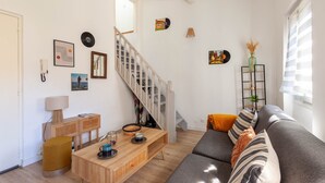 A living room with a staircase, a sofa, a coffee table, and wall decorations. - Le Nid Phocéen - À 700 m du Vieux-Port (Marseille)
