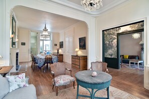 Ein geräumiges Wohnzimmer mit Essbereich, Holzboden und einer Kristallleuchter.