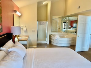 Ein Hotelzimmer mit Bett, Badewanne, Dusche und einem großen Spiegel.