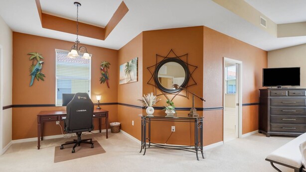 A room with a desk, chair, mirror, TV, and a dresser. - 9820 Healthpark Cir #101 (Fort Myers)