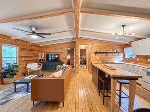 A spacious log cabin interior with a living room, kitchen, and dining area.
