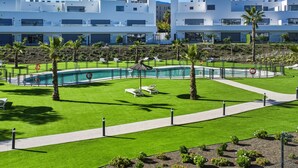 A modern hotel with a swimming pool, lounge chairs, and a well-maintained lawn. - 3024 Bright Apartment with Terrace and Pool (Bel-Air)