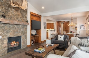 A stone fireplace, a wooden dining table, a sofa, and a chandelier in a living room. - Outpost: Grand View 363A - Air Conditioning! (Jackson)
