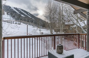 A snow-covered mountain view from a balcony with a railing and a wicker table. - Outpost: Grand View 363S - Air Conditioning! (Jackson)