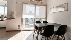A modern kitchen with a dining area, large windows, and a hanging light fixture. - Cómodo dpto. en Salta para dos personas (Salta)