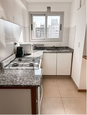 Eine moderne Küche mit weißen Schränken, einem Gasherd, einer Mikrowelle und einem Fenster mit Blick auf die Stadt.