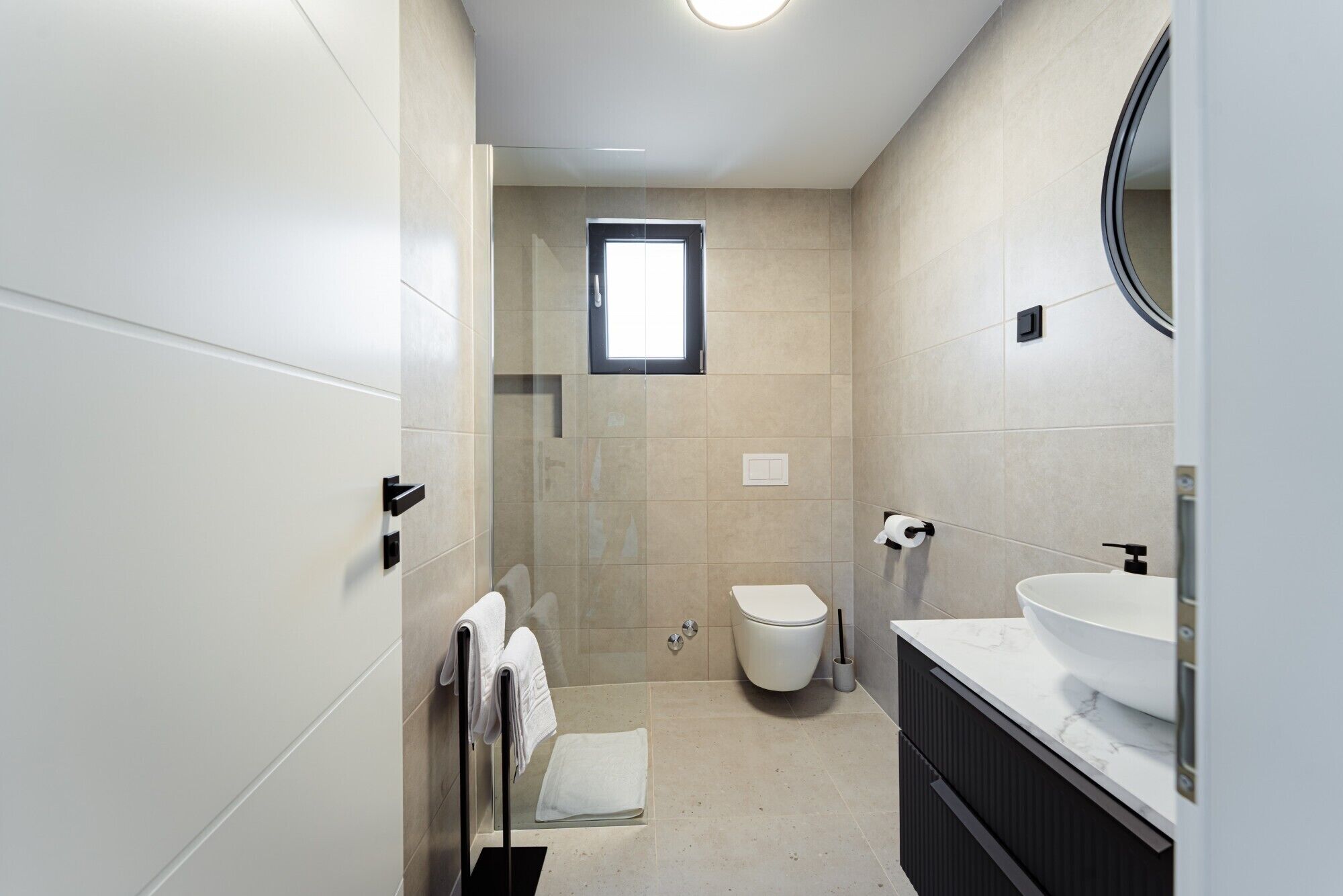 A modern bathroom with a toilet, sink, and shower area.