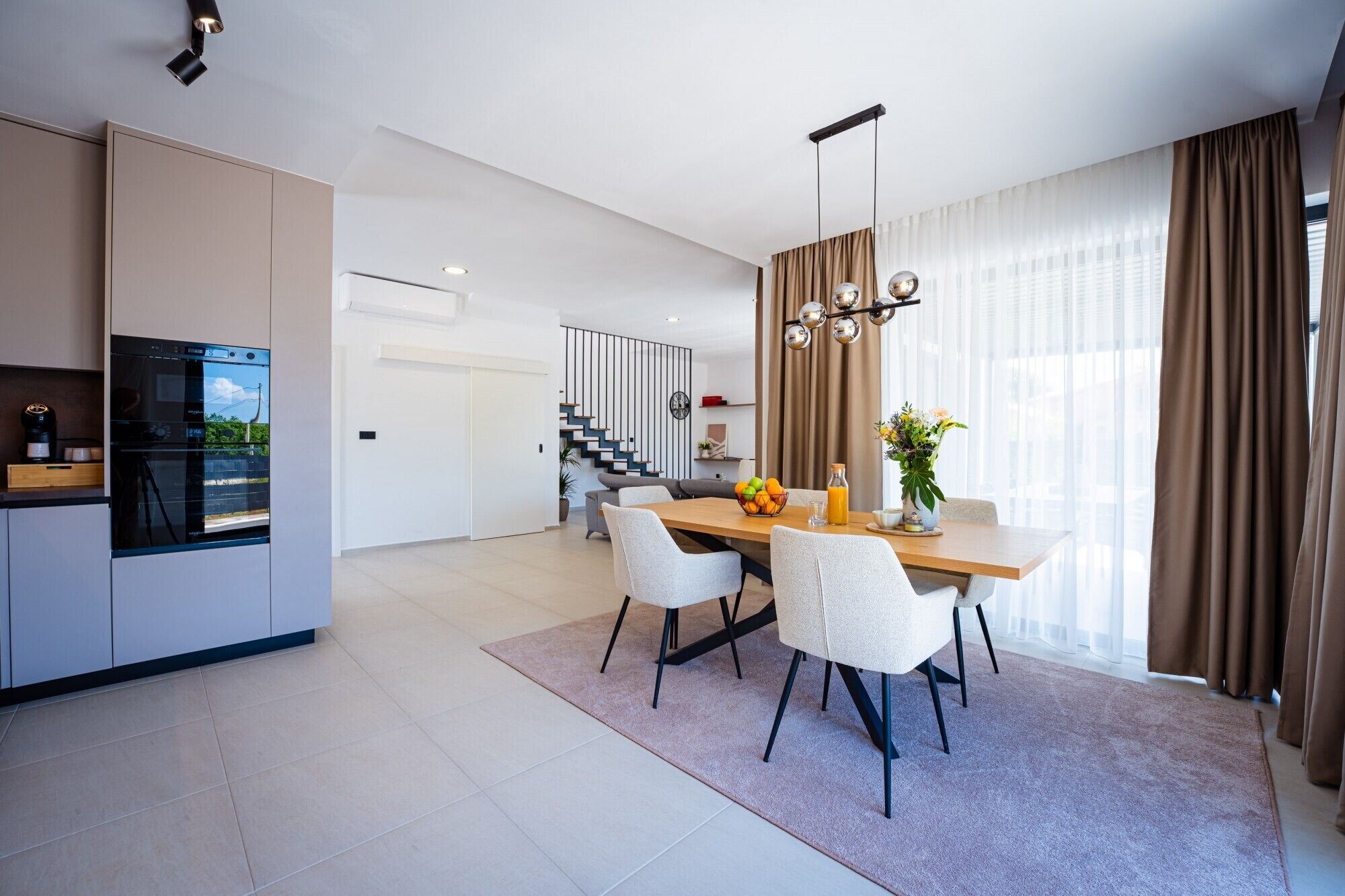 A modern kitchen with a built-in oven and a dining area with a wooden table and chairs.
