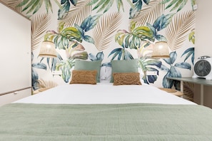 A bedroom with a bed, two pillows, a bedside lamp, and a wall-mounted fan. - Home2Book Chill Terrace & Pool Escape Costa Calma (Costa Calma)
