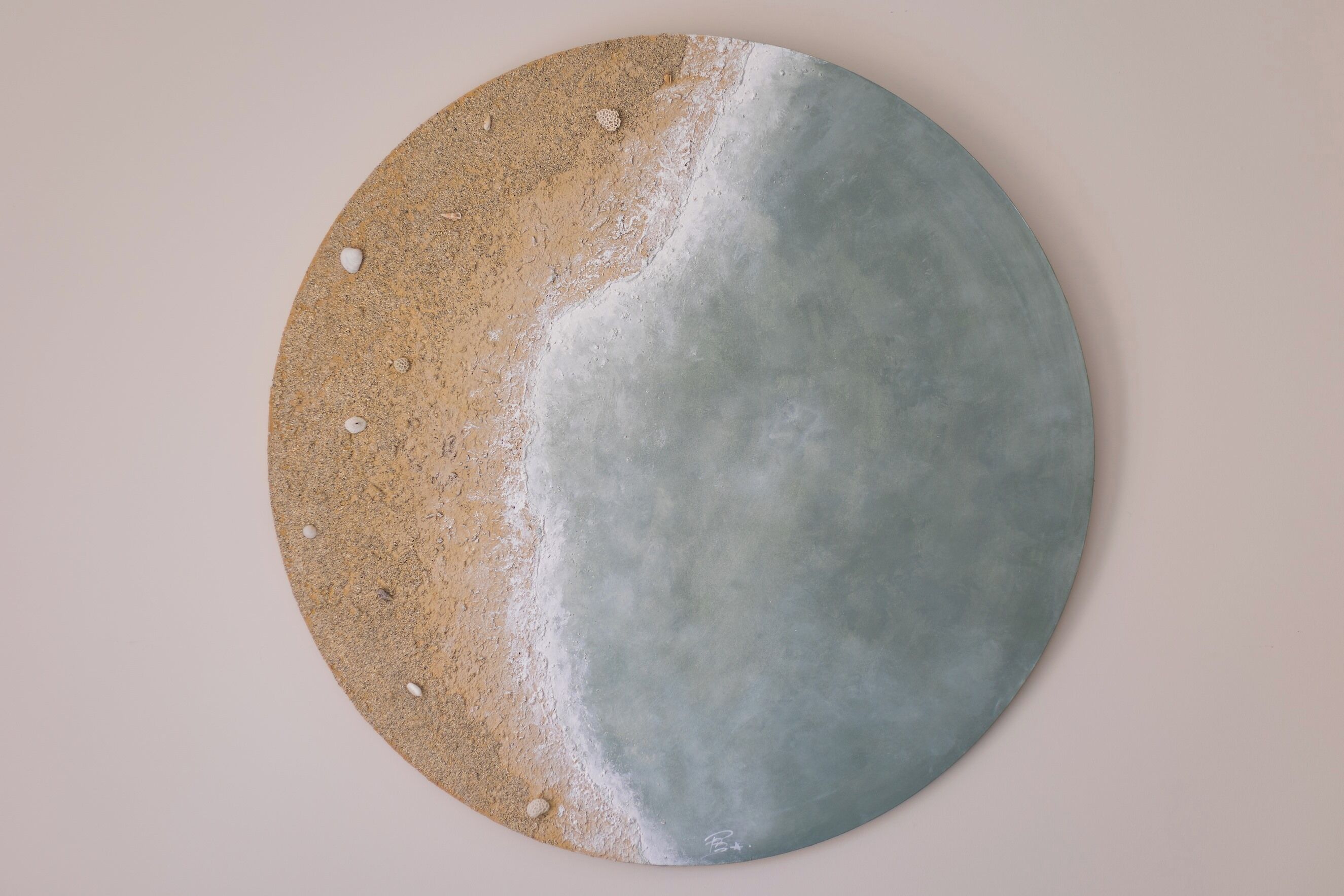 A circular artwork with a beach scene.