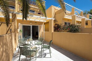 A patio with outdoor furniture, a pergola, and a building with a beige facade. - Home2Book Chill Terrace & Pool Escape Costa Calma (Costa Calma)