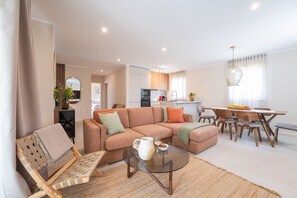 Ein modernes Wohnzimmer mit einer Couch, einem Couchtisch und einem Essbereich mit Stühlen.