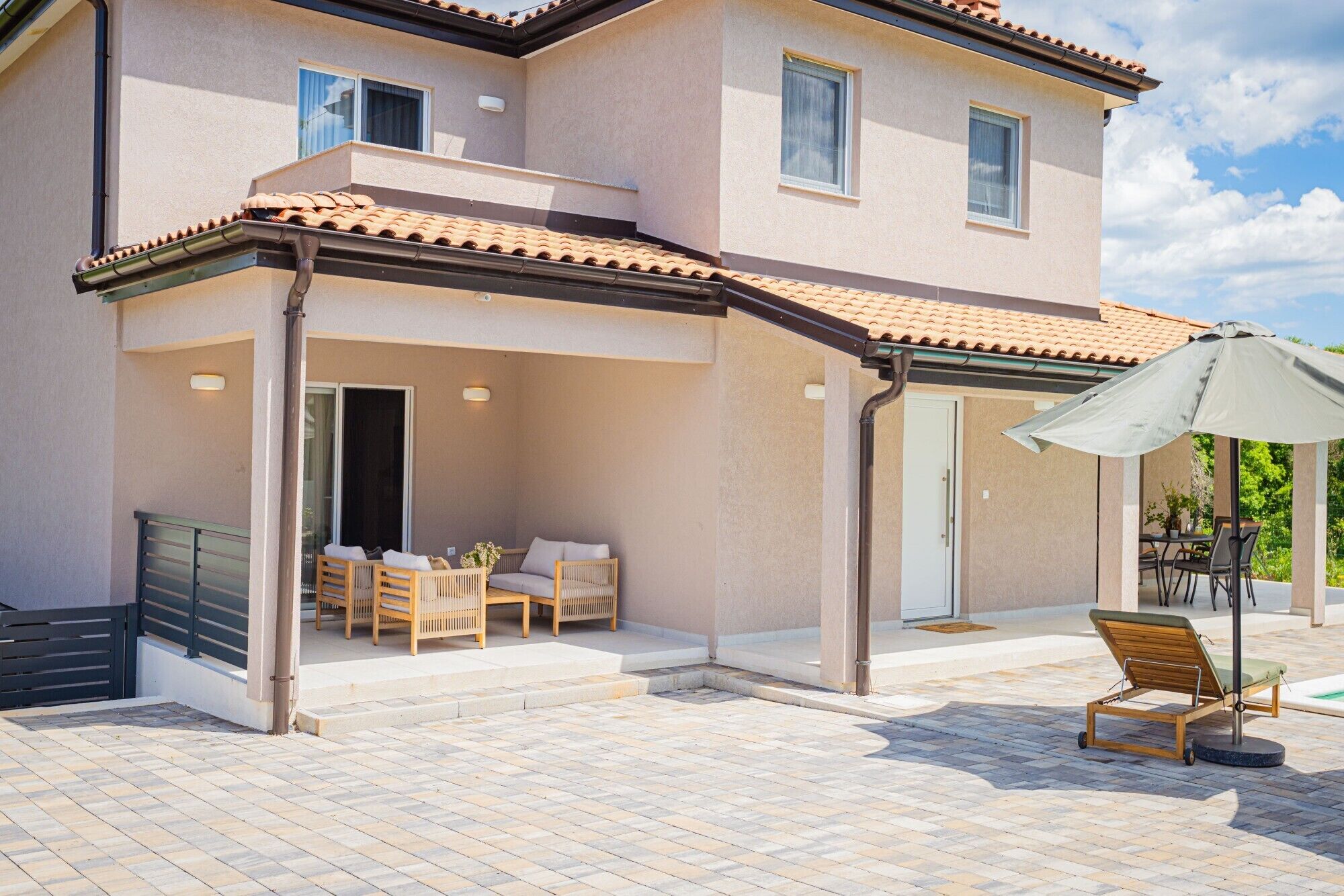 A two-story building with a covered patio area featuring outdoor furniture and a table.