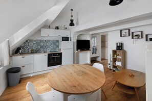 Una cocina funcional con muebles blancos, una mesa de comedor de madera y una mesita auxiliar.