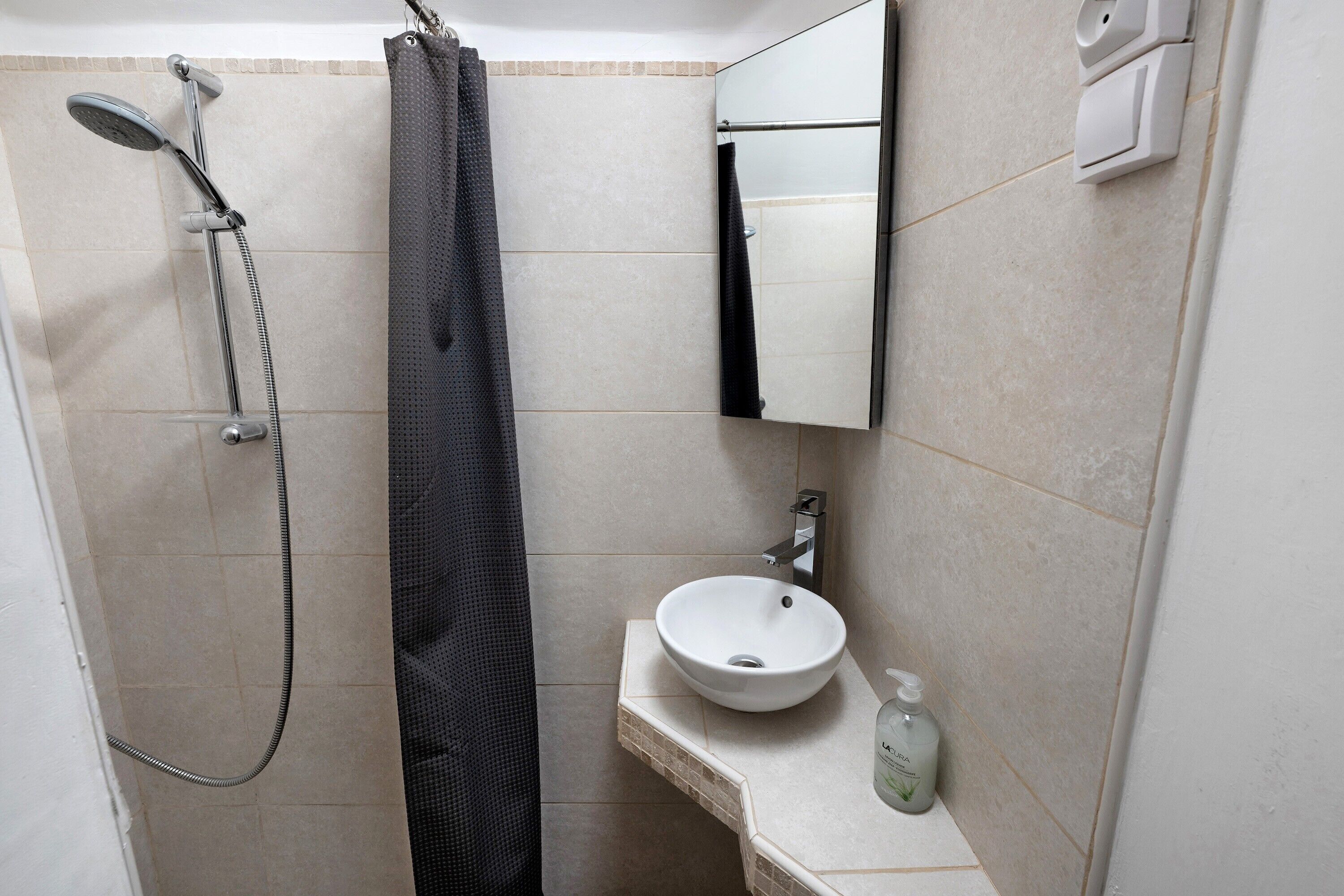 Une salle de bain équipée d’une douche, d’un porte-serviettes, d’un lavabo et d’un miroir.