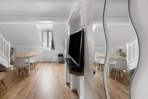 Un espacio habitable moderno y abierto con comedor, televisor y ventana.