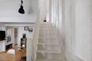 A staircase leading to a second floor with a white wall and a hanging light fixture. - Cozy Modern Apartment in Central Joigny 4' with Wi-Fi (Joigny)