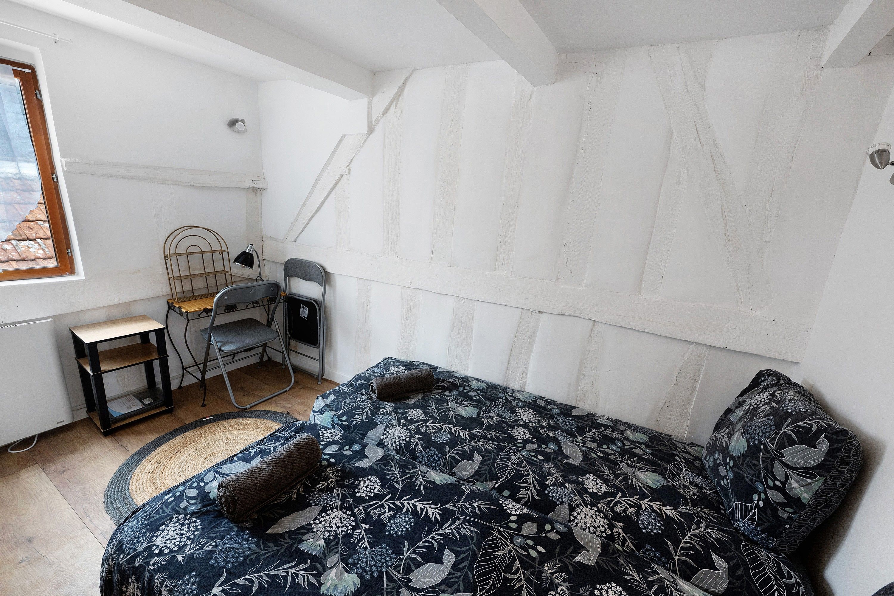 Een kleine, eenvoudig ingerichte kamer met een bed, een bureau en een stoel.