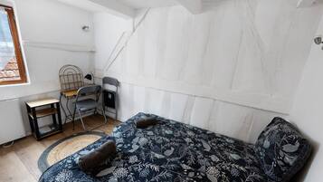 Een kleine, eenvoudig ingerichte kamer met een bed, een bureau en een stoel.