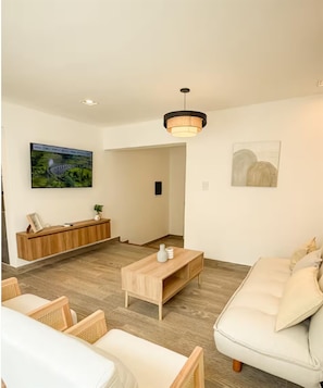 A modern living room with a sofa, coffee table, and a TV mounted on the wall. - Dpto. a media cuadra de la plaza principal 1 (Salta)