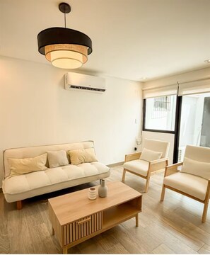 A modern living room with a sofa, two chairs, a coffee table, and a hanging light fixture. - Dpto. a media cuadra de la plaza principal 1 (Salta)
