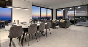Ein moderner Essbereich mit Tisch für vier Personen, einer Couch und Blick auf die Stadtlandschaft.