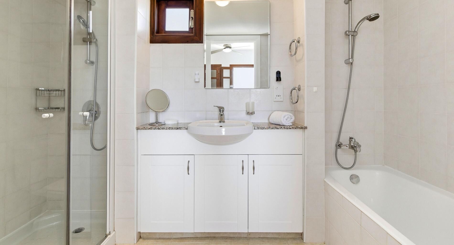Une salle de bain moderne avec une douche à l’italienne en verre, un lavabo blanc avec un miroir rond et une baignoire.