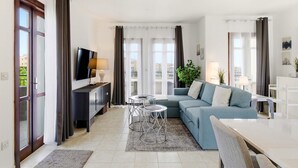 Ein modernes Wohnzimmer mit einer Couch, einem Fernseher und zwei kleinen Tischen.