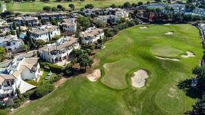 Ein Golfplatz mit Sandbunkern und eine Wohngegend mit Villen.
