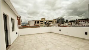 A rooftop terrace with a view of surrounding buildings, a tiled floor, and a cloudy sky. - Dpto. a media cuadra de la plaza principal 2 (Salta)