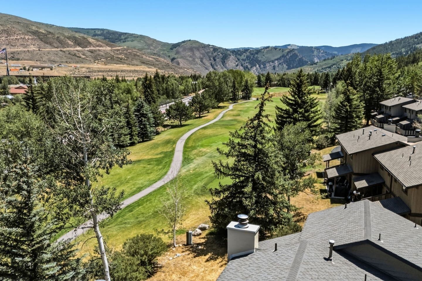 Zona residencial con un campo de golf, viviendas y montañas al fondo.