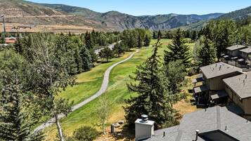 Zona residencial con un campo de golf, viviendas y montañas al fondo.