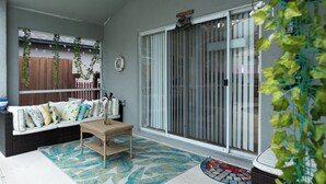 Un patio abrité comprenant un canapé, une petite table et un tapis décoratif.