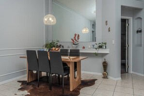Ein Essbereich mit Holztisch, schwarzen Stühlen, einem Kuhfellteppich und Pendelleuchten.