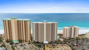 A beachfront hotel with multiple high-rise buildings, a parking area, and a view of the ocean. - Beachfront 2 Bedroom Condo Pool Sleeps 8 (Panama City Beach)