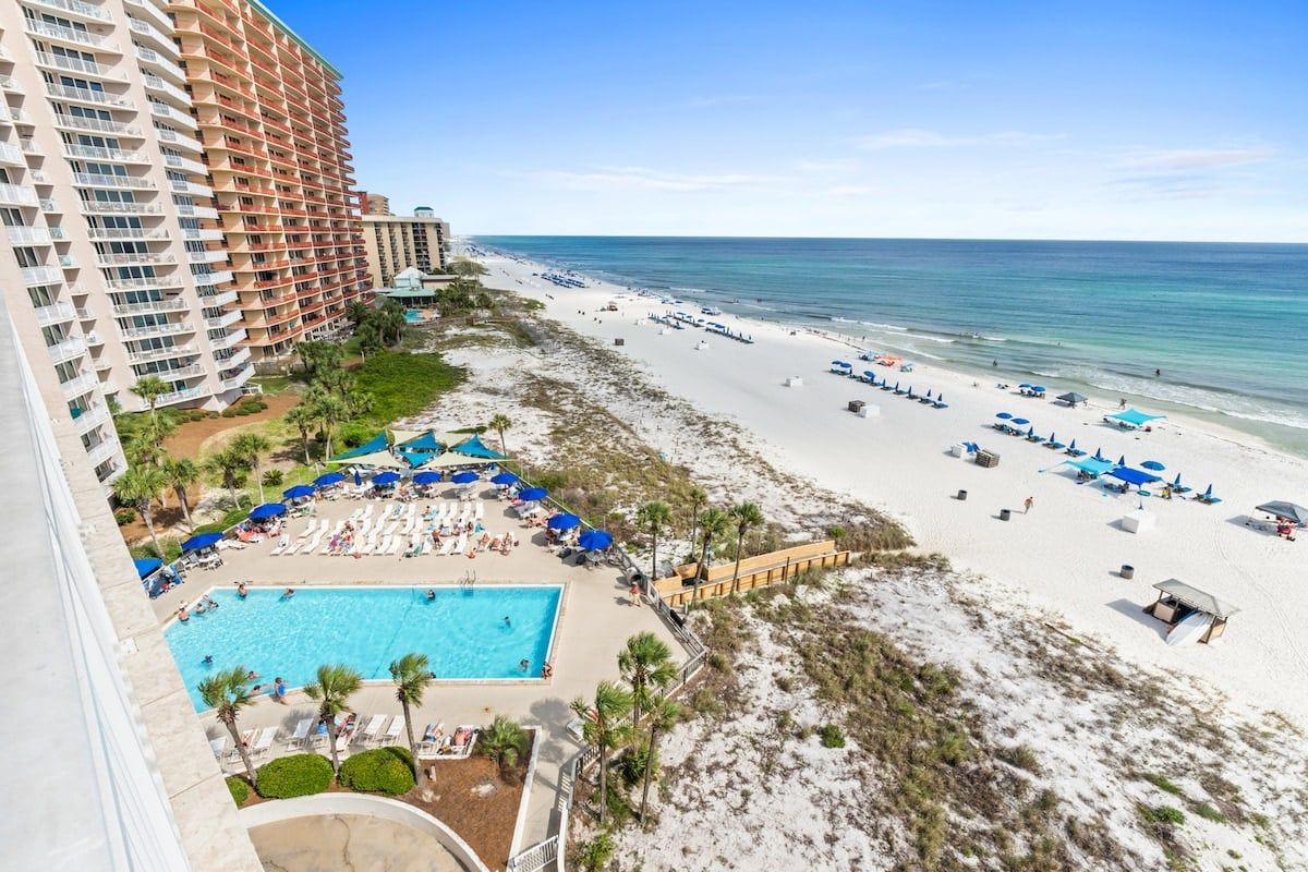 Een resort met zwembad, strand en uitzicht op de oceaan.