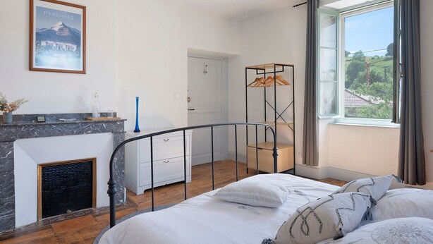 Une chambre à coucher avec un lit, une cheminée, une fenêtre donnant sur un beau paysage et une porte.
