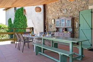 An outdoor patio with a table and chairs, a stone wall, and a green door.