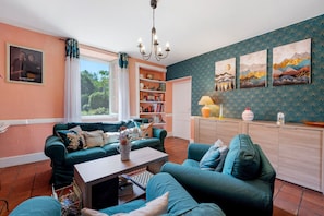 A cozy living room with teal sofas, a bookshelf, and artwork on the wall. - Baladous Guest Room – Arbas with Shared Terrace, Wi-Fi, and Air Conditioning (Montgaillard-de-Salies)
