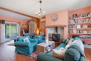Un salon chaleureux avec des canapés de couleur turquoise, une table basse en bois, une cheminée et une bibliothÚque remplie de livres.