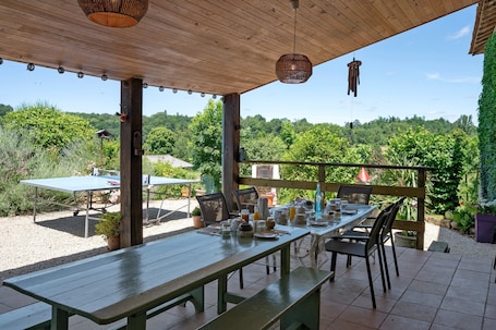 An outdoor patio with a wooden table set for dining, surrounded by chairs, and a view of a forested landscape.. Rioutord Guest Room with Shared Terrace, Wi-Fi, and Air Conditioning