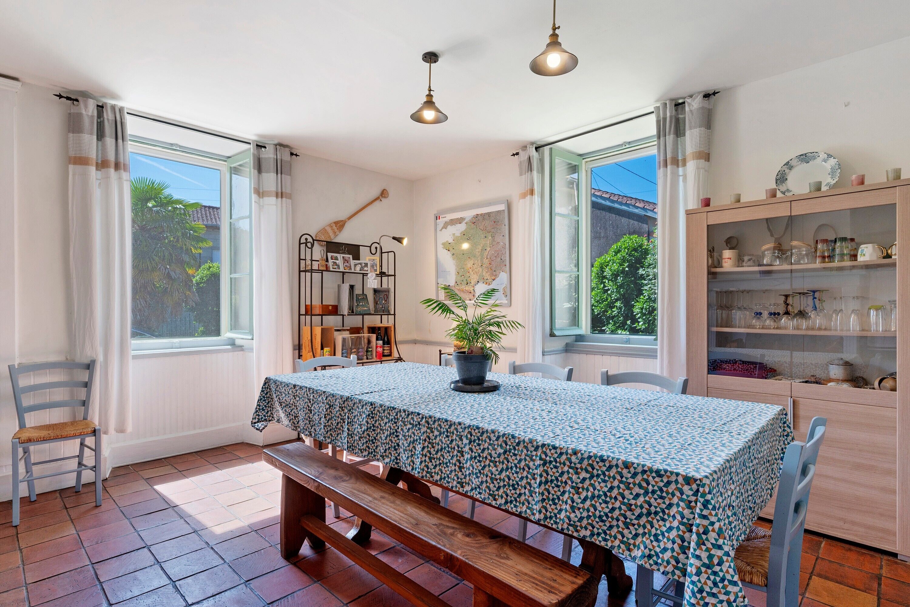 A dining area with a table set for four, a bench, a bookshelf, and a cabinet with glass doors.