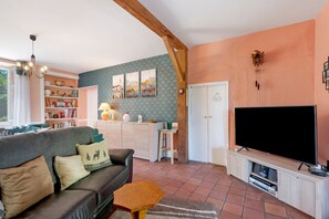 A living room with a sofa, a television, a bookshelf, and a kitchen area.