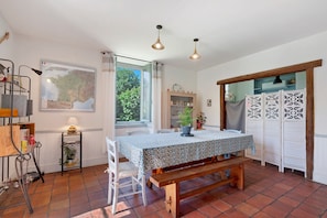 Un coin repas comprenant une table, des chaises, un banc, une carte accrochée au mur et une fenêtre avec des rideaux.