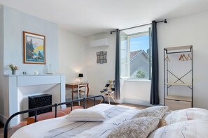 Une chambre à coucher comprenant un lit, un bureau, une chaise, une fenêtre et un porte-manteau.