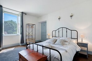 Une chambre Ă coucher avec un lit, une table de chevet, une lampe et un banc en bois.