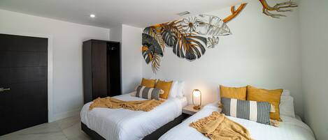 Un dormitorio moderno con dos camas, un armario oscuro y un mural en la pared.