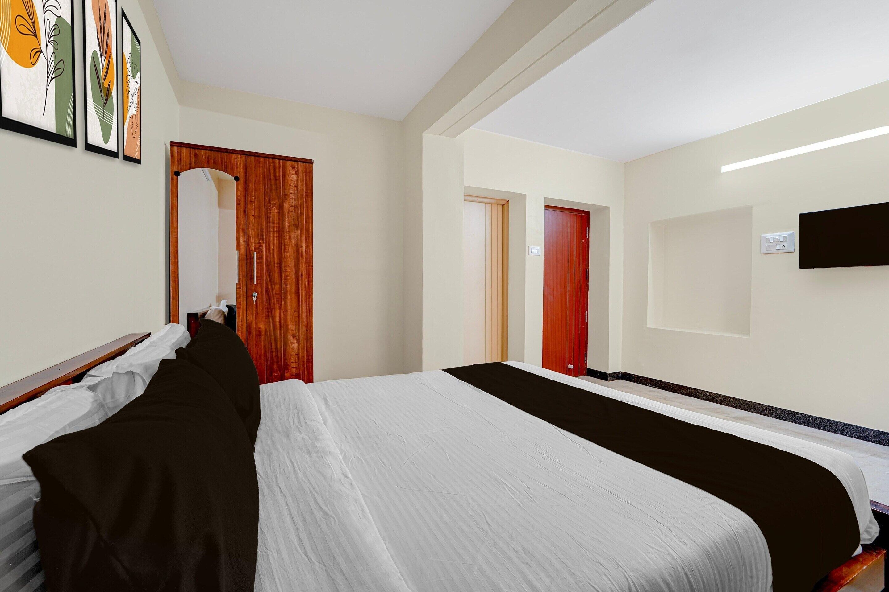 Een hotelkamer met een groot bed, een houten deur, een televisie en kunst aan de muur.
