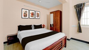 A bedroom with a bed, a ceiling fan, a wardrobe, and framed artwork on the wall.